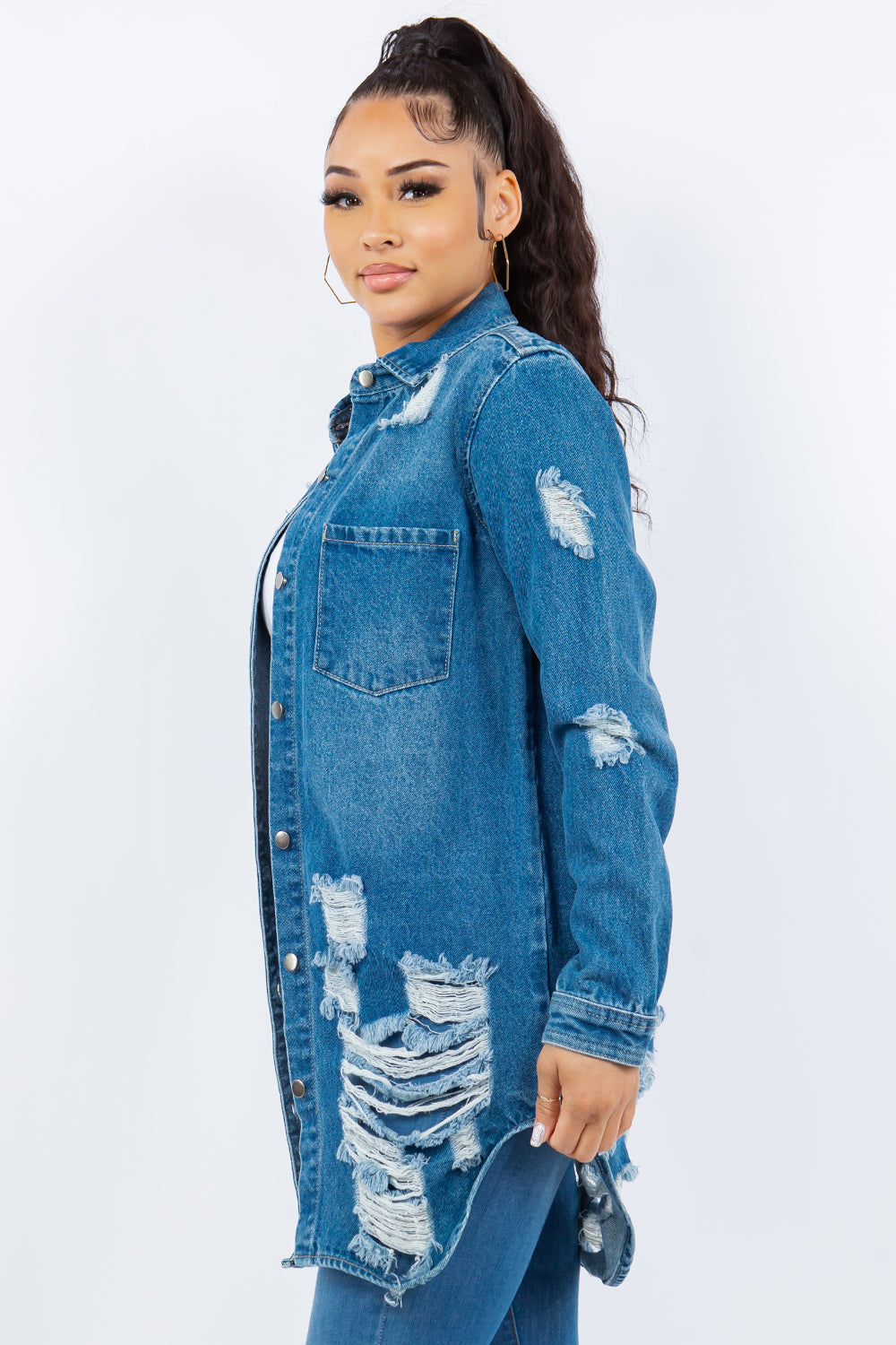 Woman wearing an American Bazi Distressed Button Up Long Sleeve Denim Jacket over a white crop top and blue jeans, standing against a plain background.