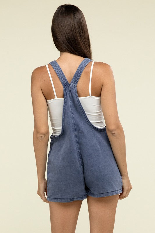 A person wearing the Washed Knot Strap Romper and a white tank top stands against a plain background.