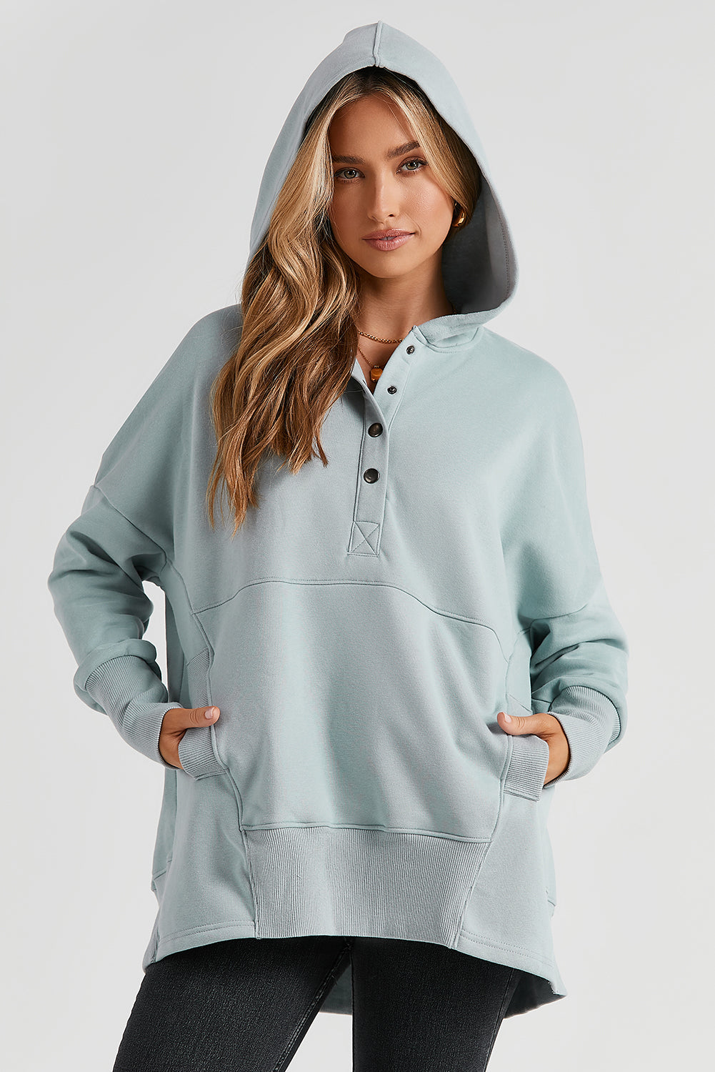 A person with long hair is smiling and looking over their shoulder while wearing a Gray Batwing Sleeve Pocketed Henley Hoodie.