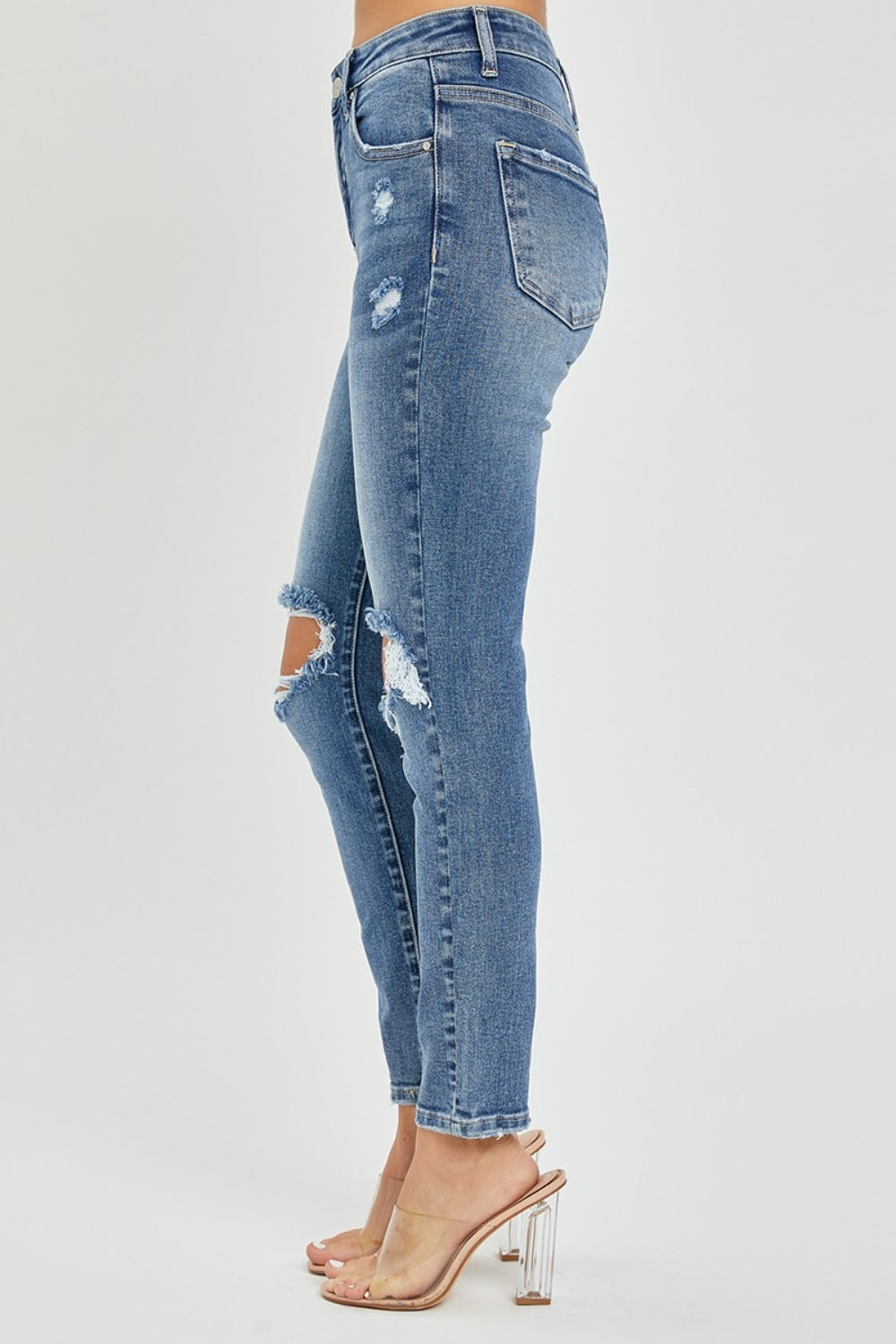 Person wearing the Risen Full Size High Rise Knee Distressed Skinny Jeans and clear heels, posing against a plain background.