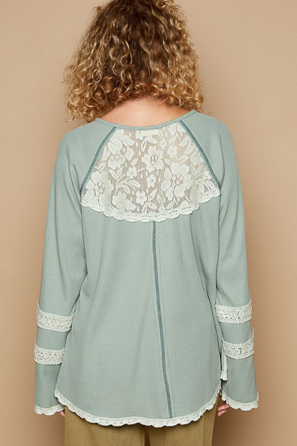 A woman with curly hair wears a pastel green POL Round Neck Long Sleeve Lace Trim Thermal Top with buttons on the front, standing against a plain beige background.