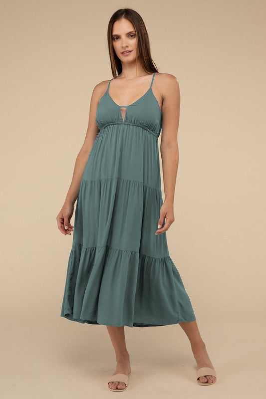 A woman wearing a teal woven sweetheart neckline tiered cami midi dress and sandals, standing against a neutral background.