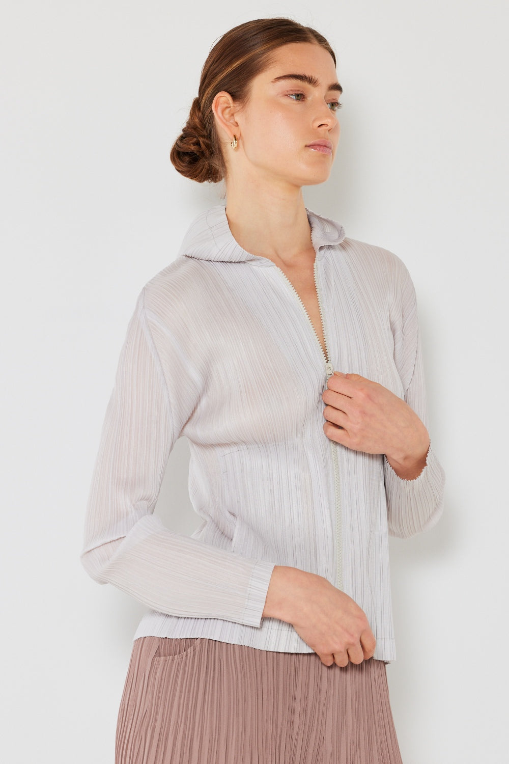 A person wearing the Marina West Swim Pleated Hood Jacket with hands in pockets, showcasing its convenient 2-way zipper, stands against a plain white background.