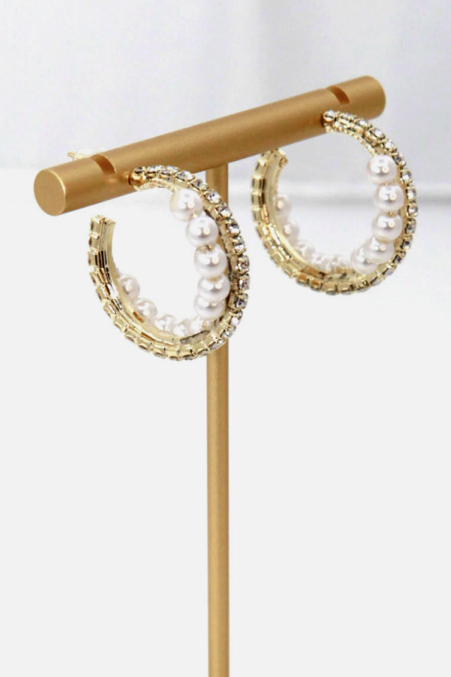 Alloy Pearl Hoop Earrings featuring gold hoops with imitation pearls and small clear gemstones, showcased on a vertical stand.