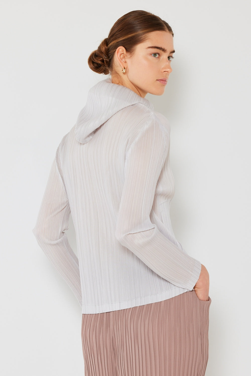 A person wearing the Marina West Swim Pleated Hood Jacket with hands in pockets, showcasing its convenient 2-way zipper, stands against a plain white background.