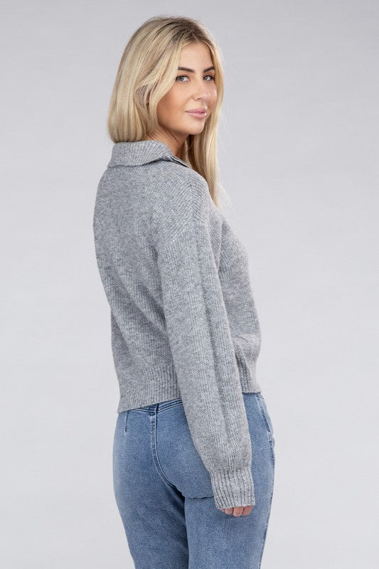 A person with long blonde hair wears a stylish cozy top—an Easy-Wear Half-Zip Pullover in grey—and blue jeans while looking down.