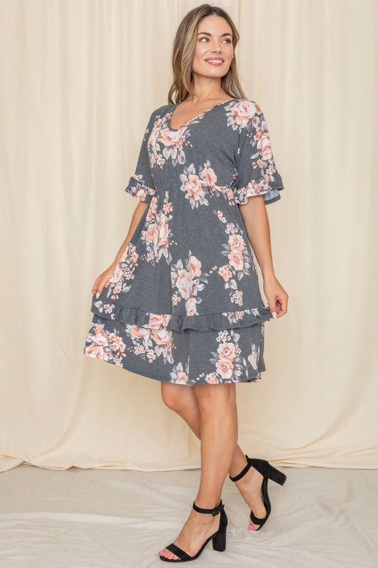 A woman wearing a Floral V Neck Ruffle Dress stands indoors, posing with one hand on her hip.