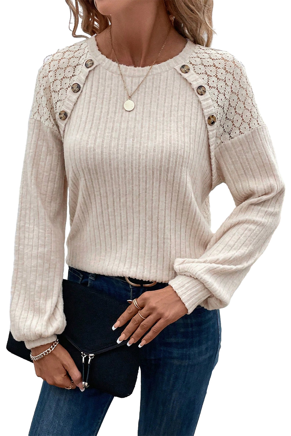 A woman dressed in the Parchment Contrast Lace Raglan Sleeve Buttoned Ribbed Top paired with blue jeans, a pendant necklace, and bracelets. She is holding a black clutch bag and has a hand on her waist.