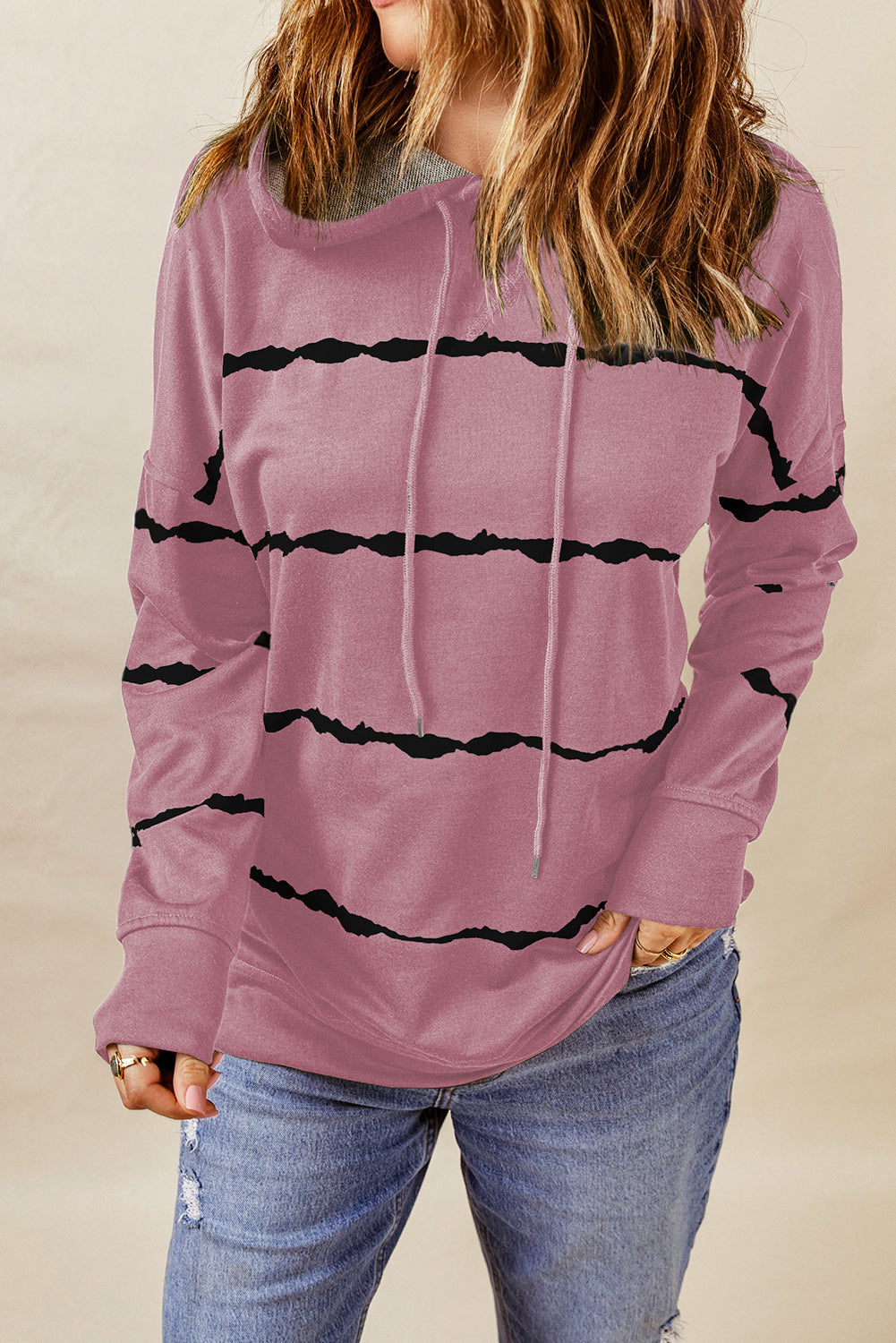 A person with wavy, light brown hair is wearing a Pink Tie-dye Striped Drawstring Hoodie with Side Split Tops and blue jeans, viewed from the back. The relaxed silhouette of the hoodie adds to its casual appeal.