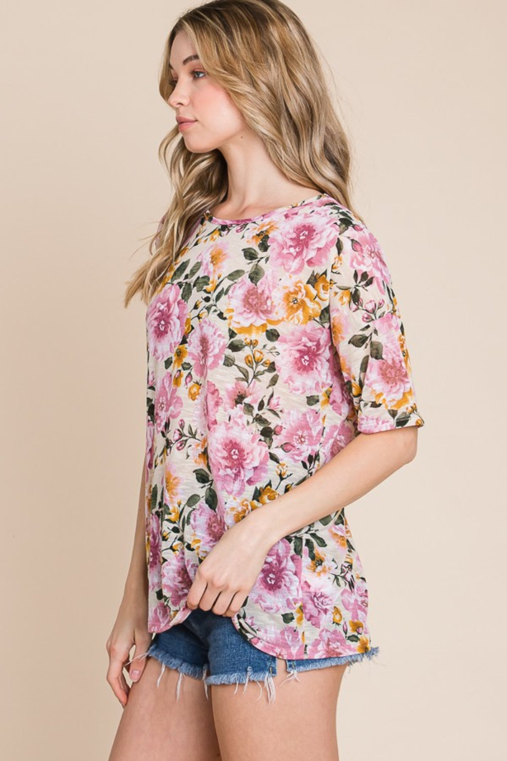 Wearing the BOMBOM Floral Round Neck T-Shirt and denim shorts, a person effortlessly embodies casual elegance against a plain beige background.