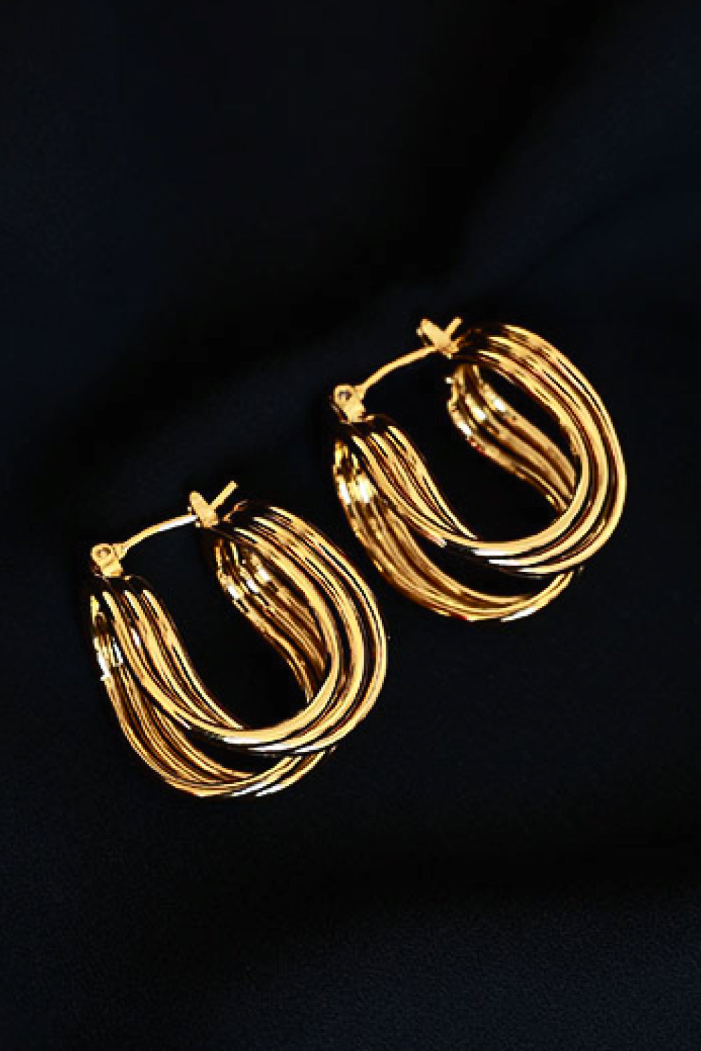 The U-Shaped Hoop Earrings feature a layered, wavy design on a light background, making them a stunning addition to any jewelry collection. These exquisite brass earrings showcase elegant craftsmanship, perfect for both casual and formal occasions.