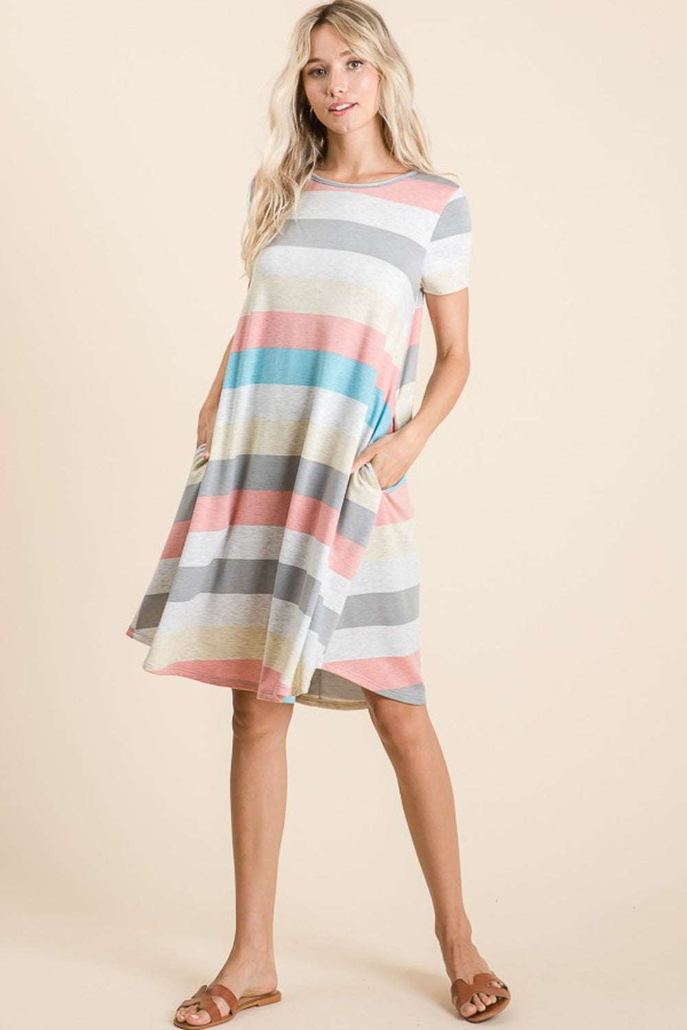 A woman is wearing the BOMBOM Striped Short Sleeve Dress, showcasing multicolored patterns and practical pockets for a casual look.