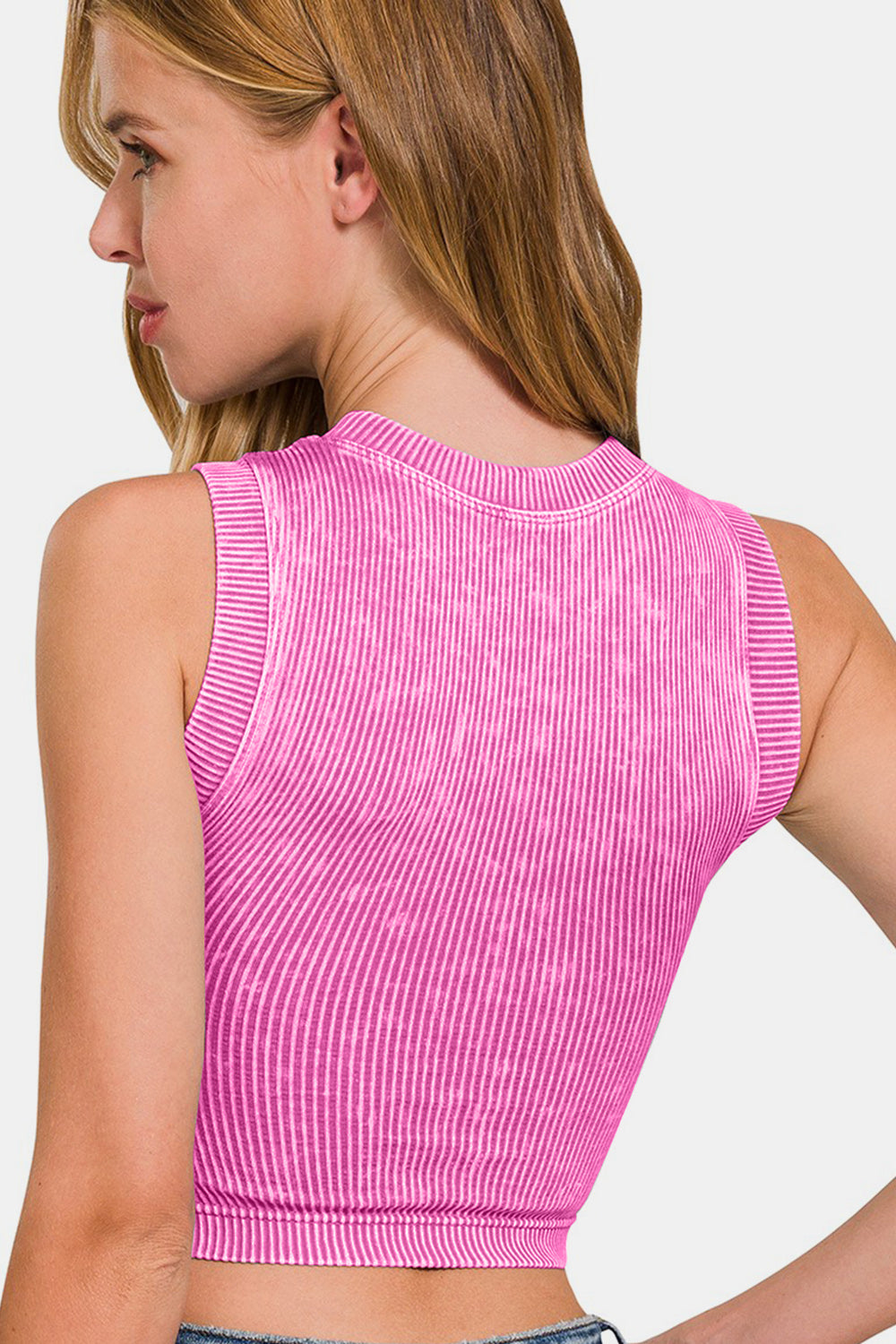 A woman with blonde hair is wearing a pink Zenana Washed Ribbed Seamless Crop Tank with Bra Pad. She is looking slightly down and to the side.