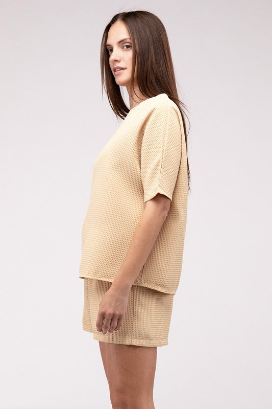 Clad in the Waffle Round Neck Top and Short Set paired with black sunglasses, a person stands against a plain beige background, highlighting the non-stretch polyester fabric.