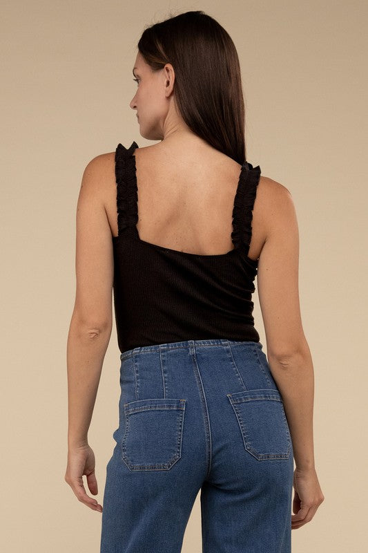 A young woman in a chic Ribbed Ruffle Strap Bodysuit and ripped denim shorts poses against a plain background.