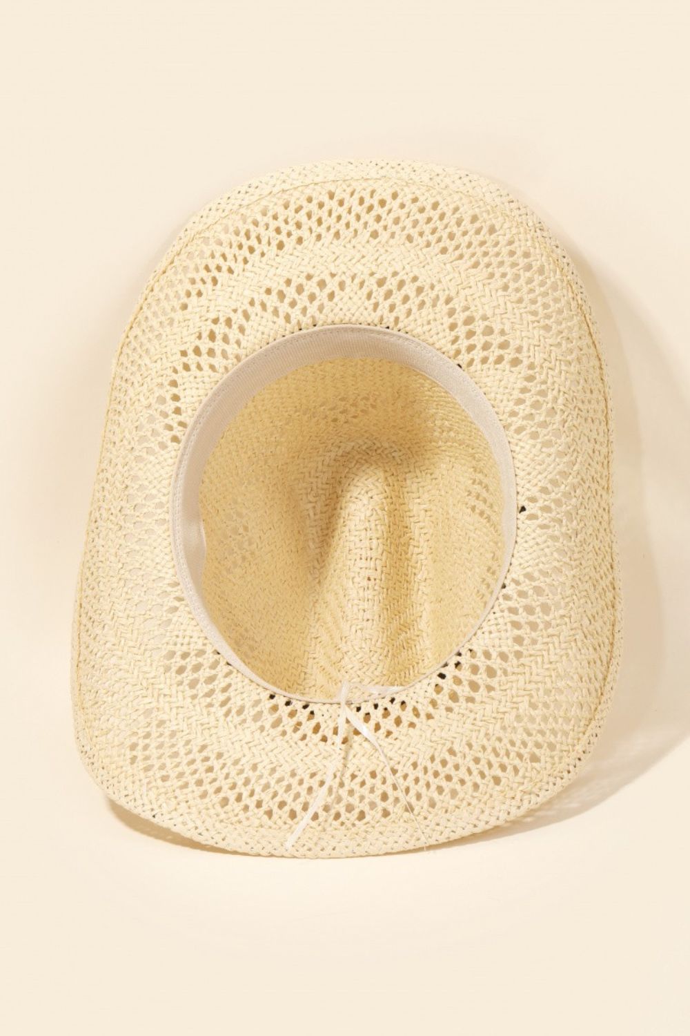 A wide-brimmed, light-colored Fame Straw Weave Rope Ribbon Cowboy Hat featuring intricate cutout designs.