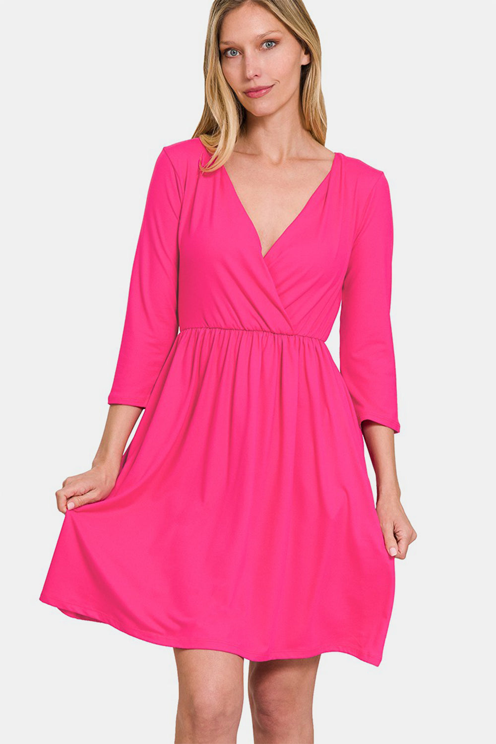 A woman in a pink Zenana Three-Quarter Sleeve Surplice Dress with Pockets stands against a white background.