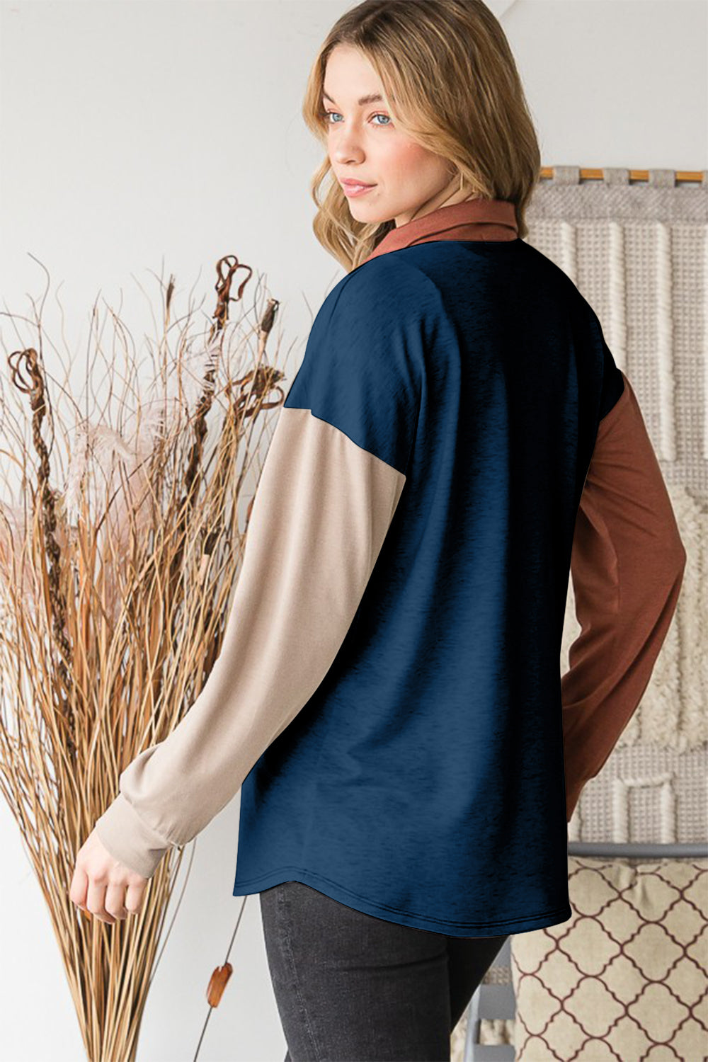 A woman stands indoors wearing the Heimish Full Size Color Block Button Down Shirt, set against a backdrop of a woven tapestry, highlighting her versatile wardrobe.