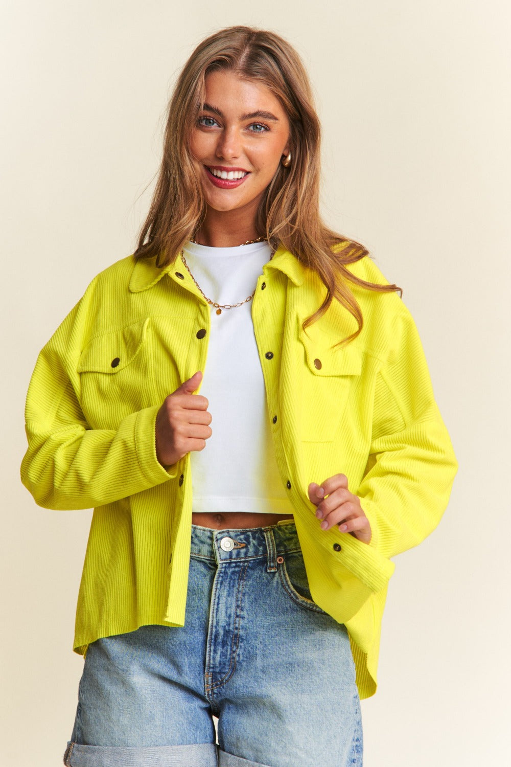 Person wearing a relaxed fit, bright yellow J.NNA Snap Down Long Sleeve High Low Shacket over a white top and denim jeans, smiling against a neutral background.