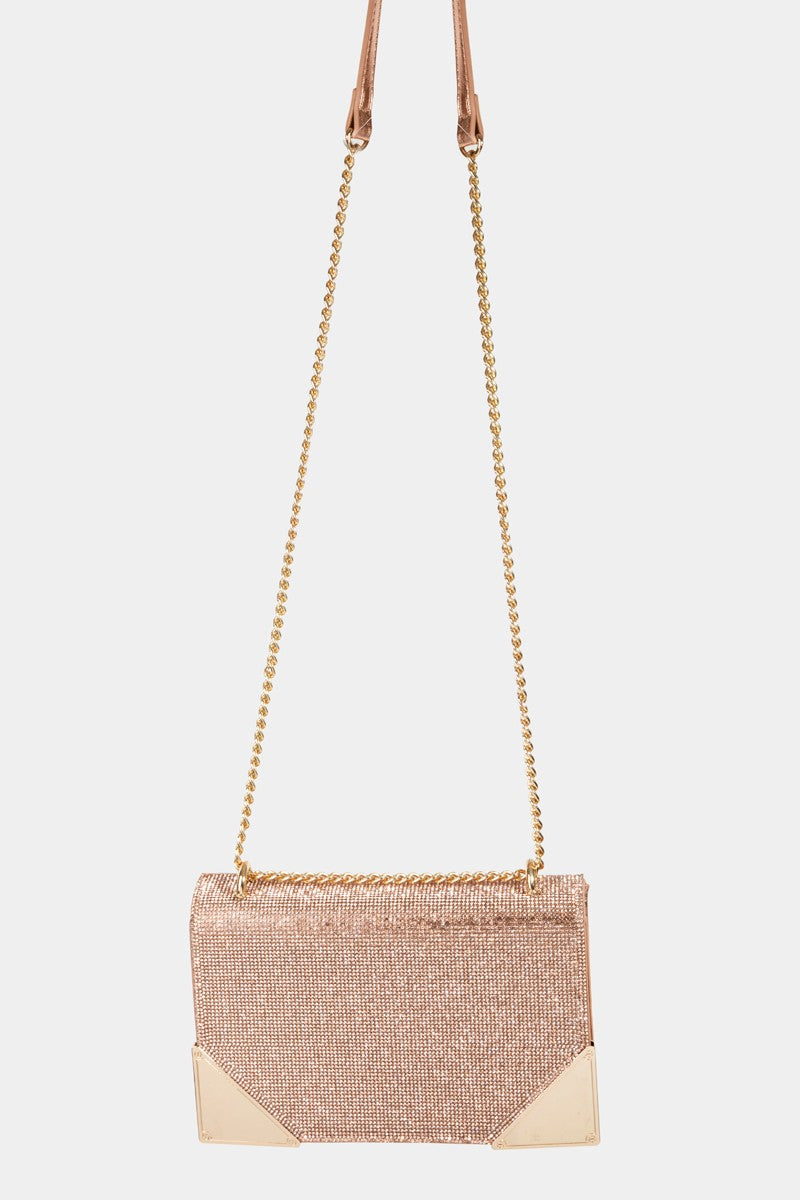 The Fame Rhinestone Studded Rectangle Crossbody Bag is a glamorous pink shoulder bag featuring a gold chain strap and metal corners, making it the perfect medium PU bag to add a touch of elegance to any outfit.