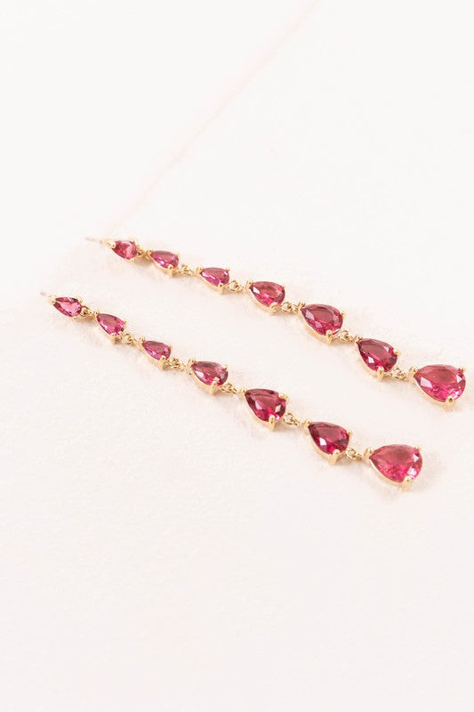 A pair of Droplet Wonder Dangle Earrings with red gemstones and sterling silver posts on a light background.