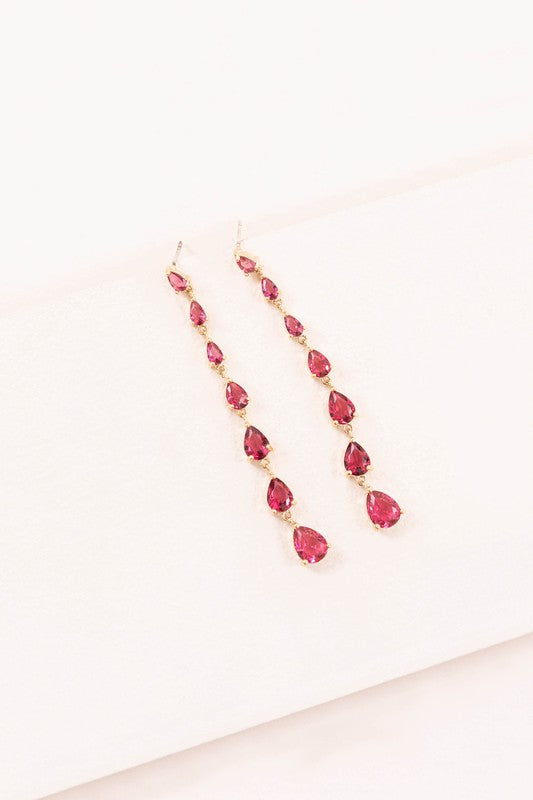 A pair of Droplet Wonder Dangle Earrings with red gemstones and sterling silver posts on a light background.