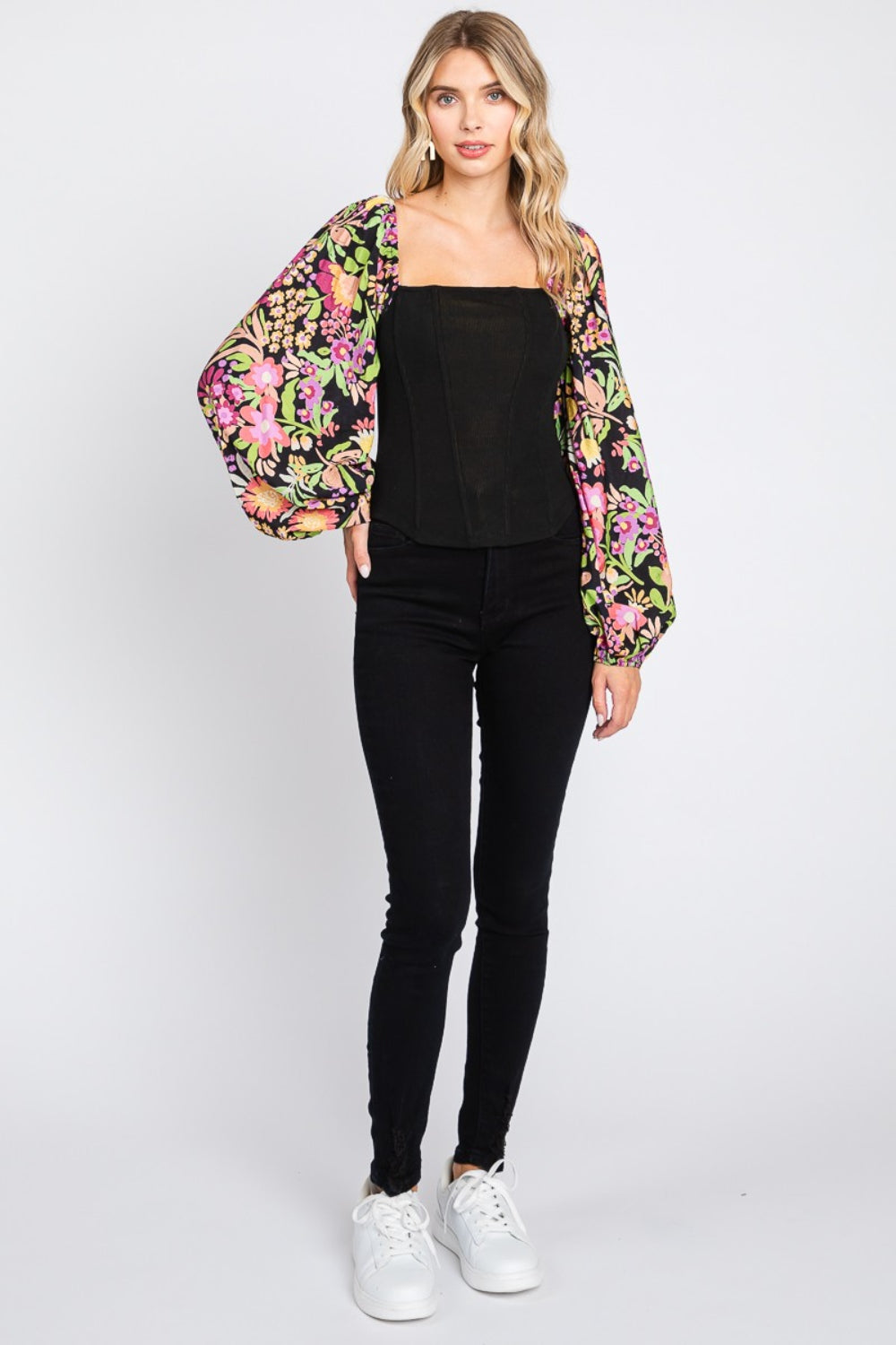 A woman wearing the chic ODDI Full Size Floral Balloon Sleeve Blouse poses against a plain background, showcasing this versatile piece.