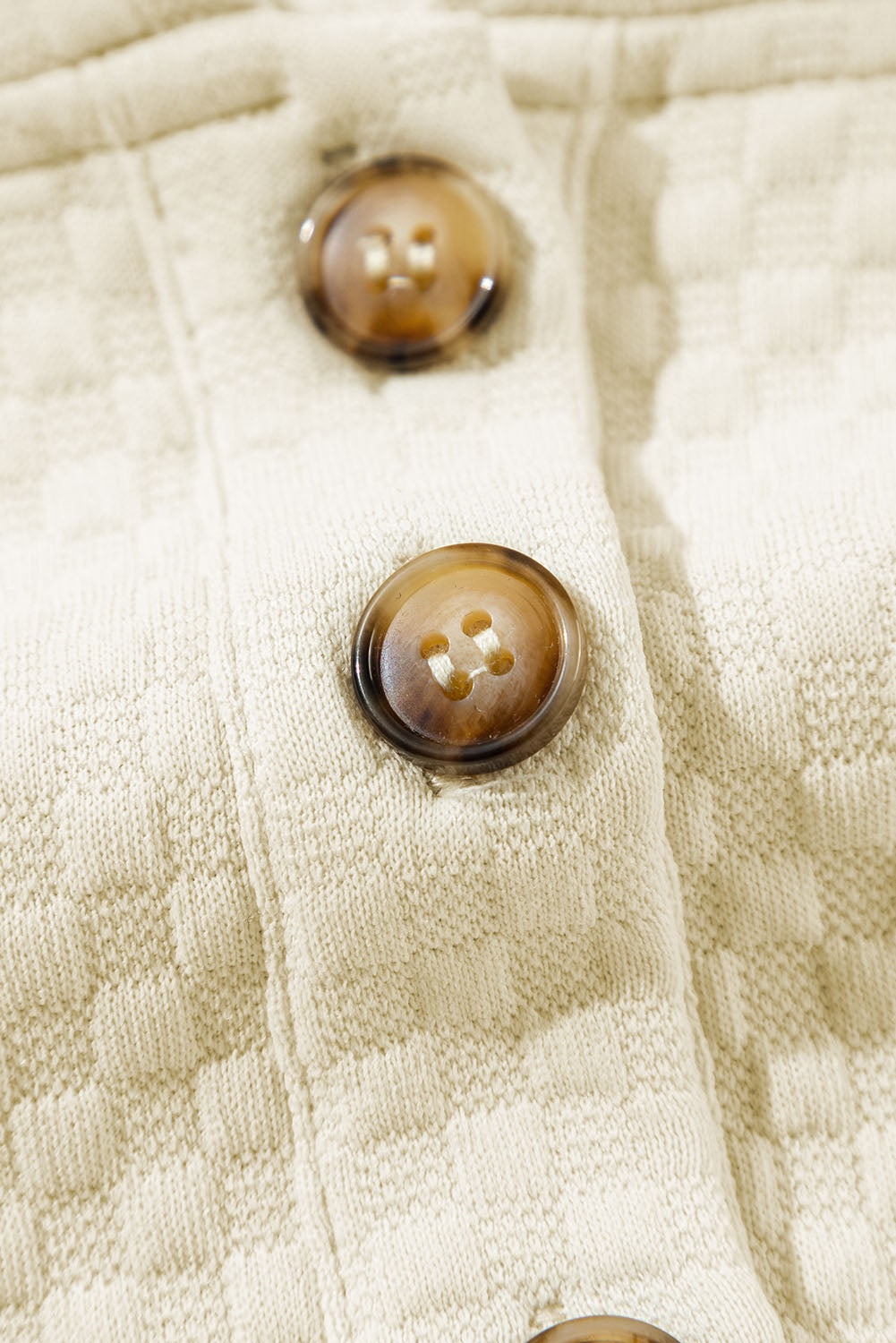 A person stands indoors facing away, wearing the Apricot Textured Buttoned Neckline Side Pockets Hoodie and black shorts. Their hand rests on their hip.