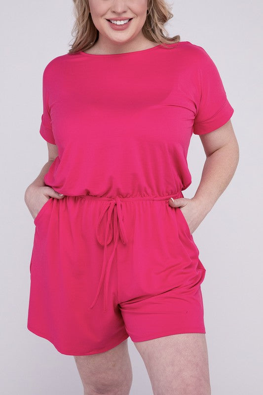 A person is wearing the Plus Brushed DTY Romper with Pockets in bright pink, smiling as they pose with one hand on their head and the other tucked into a pocket, all set against a gray background.