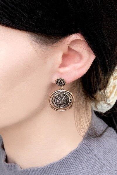 Pair of Setting Sun Drop Earrings with ornate gold patina metalwork on a white background.