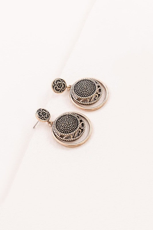 Pair of Setting Sun Drop Earrings with ornate gold patina metalwork on a white background.