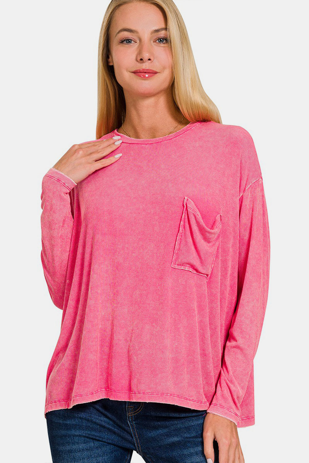 A person wearing the Zenana Round Neck Long Sleeve T-Shirt, known for its comfortable and stylish loose fit, complete with a front pocket in pink, paired with blue jeans effortlessly embodies a versatile staple.