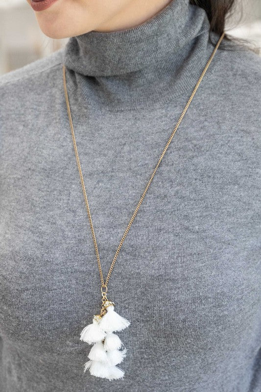 Bijou Tassel Necklace with red tassel pendant on a white background. This bohemian jewelry piece adds a vibrant touch to any ensemble.