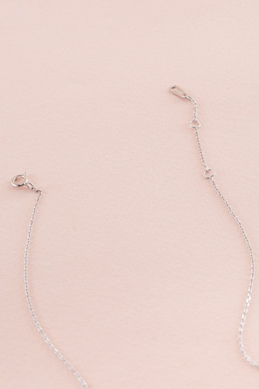 Sapphire Falls Necklace with sapphire gemstones pendants on a pink background.