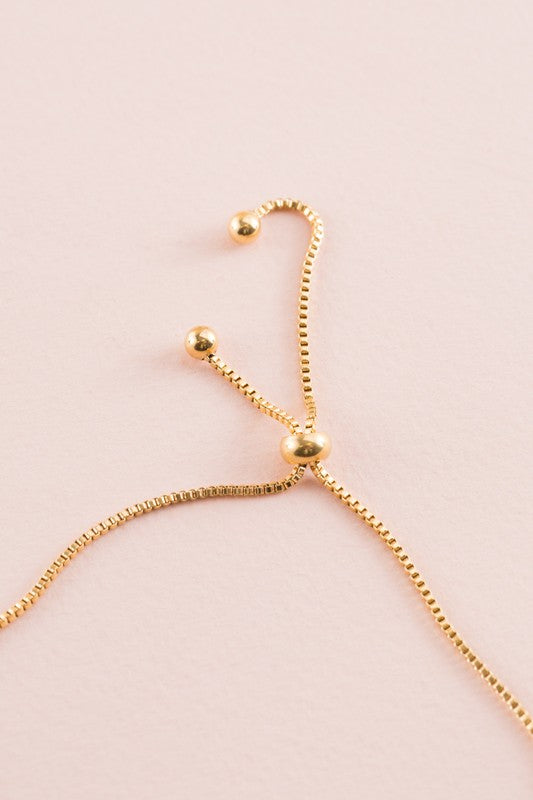 Seed of Life Bolo Bracelet with 14k gold plating, featuring a circular pendant and decorative beads on a pink background.