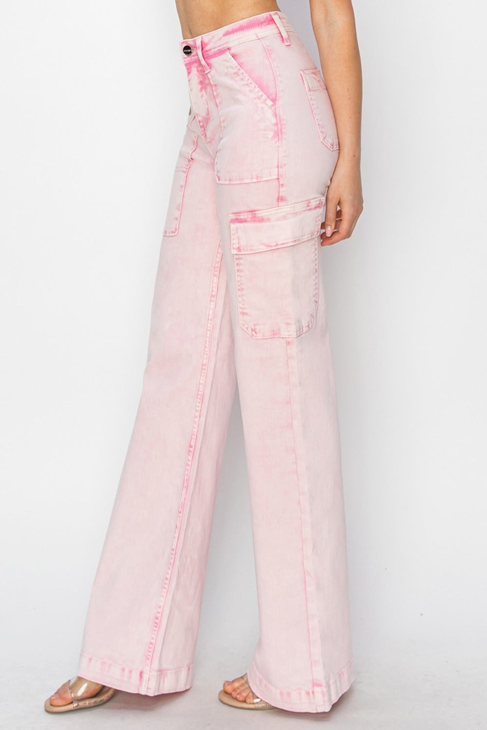 Person wearing the RISEN Full Size High Rise Wide Leg Cargo Pocket Jeans in light pink, featuring front pockets and a button-zip closure, standing against a white background.