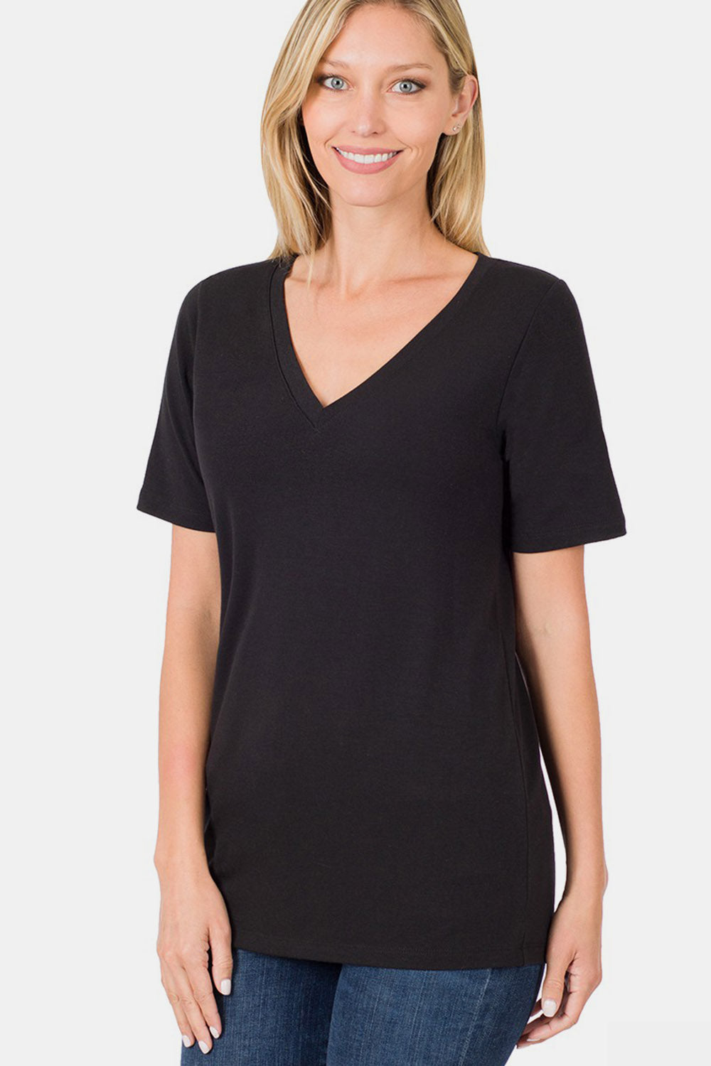 A woman with blonde hair is wearing the Zenana V-Neck Short Sleeve T-Shirt in black, made of breathable fabric, paired with blue jeans. She is standing against a plain white background, smiling. Perfect for everyday wear.