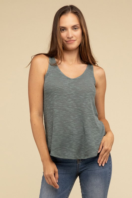 A woman in a stylish and adaptable V Neck Sleeveless Cami Top paired with jeans stands against a beige background. She has long brown hair and maintains a neutral expression.