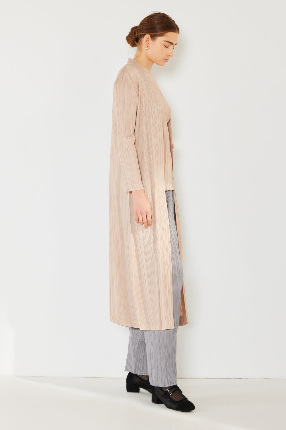 A person wears the Marina West Swim Pleated Long Sleeve Cardigan over a matching top and gray wide-leg pants, standing against a plain light background. This versatile layering piece, with its chic pleated long sleeves, adds an elegant touch to the ensemble.