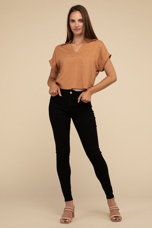 A woman with long hair is wearing the Always a Delight Short Sleeve Linen Top in brown and black pants, standing against a beige background.