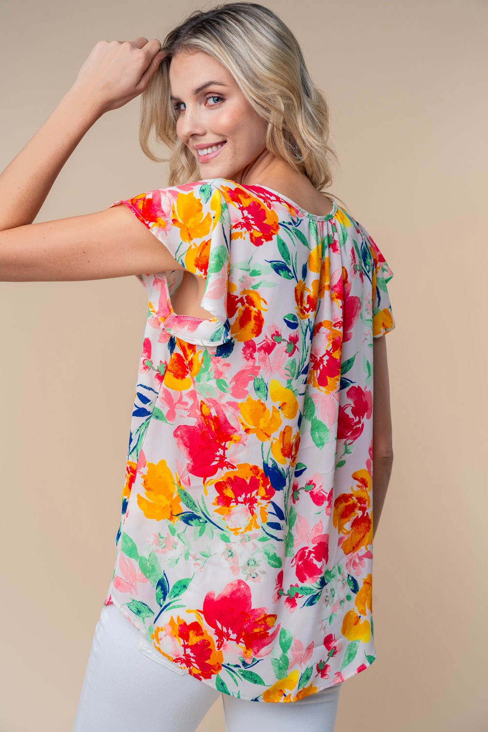 A woman wearing a White Birch Full Size Short Sleeve Floral Woven Top stands against a neutral background.