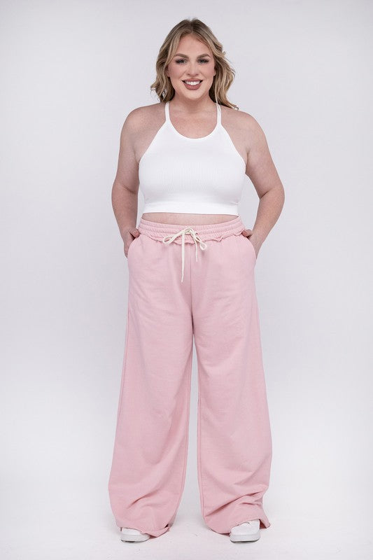 A person wearing the Plus F/Terry Drawstring Waist Raw Edge Hem Pants in pink, paired with white shoes, stands against a plain background.