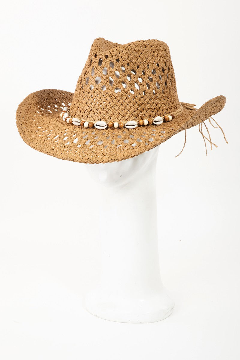 The Fame Cowrie Shell Beaded String Straw Hat, featuring cowrie shells and decorative beads, sits elegantly on a white mannequin head.