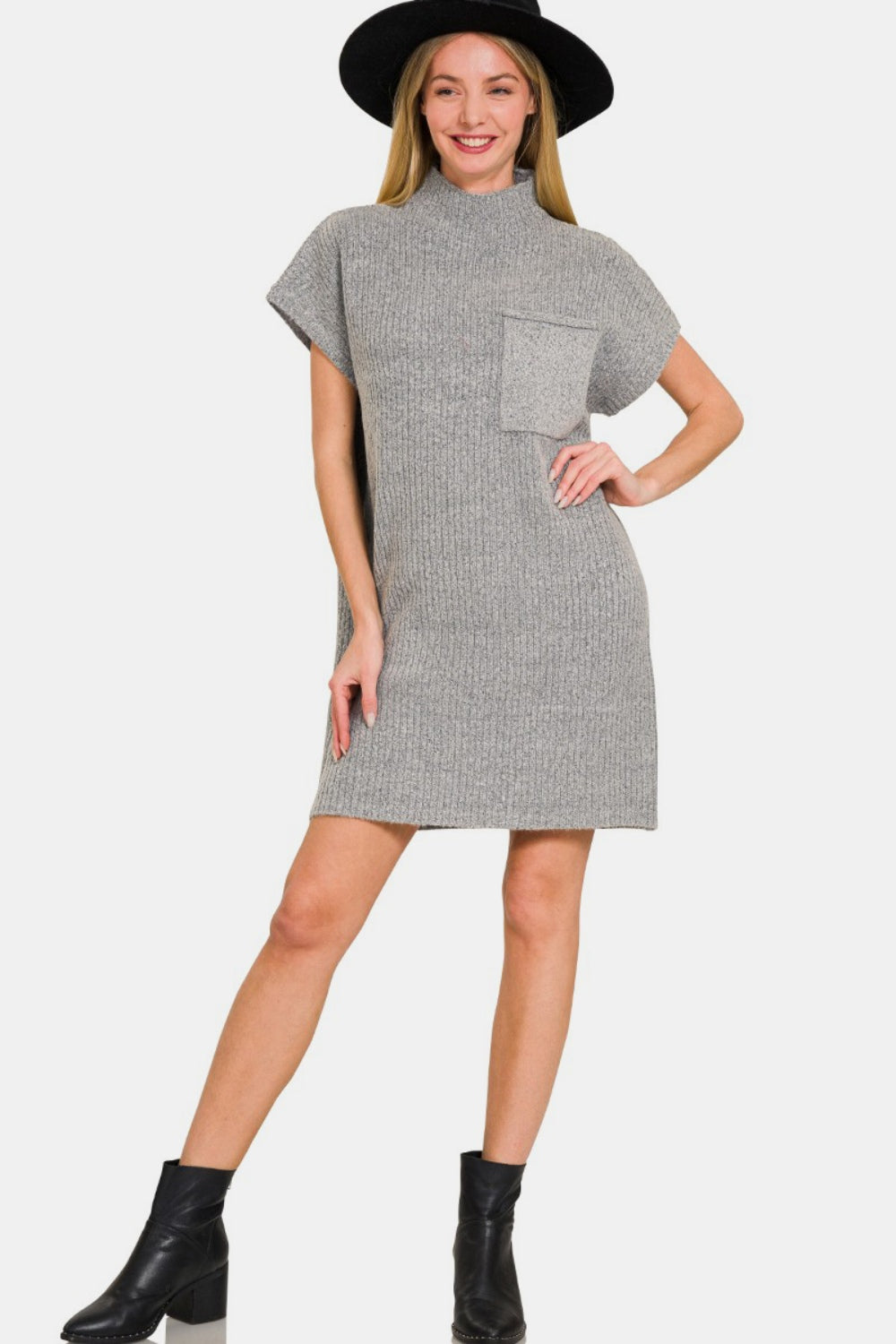 A woman smiles as she wears the Zenana Short Sleeve Sweater Mini Dress in gray, paired with a black wide-brimmed hat. This versatile outfit exudes effortless style and charm.