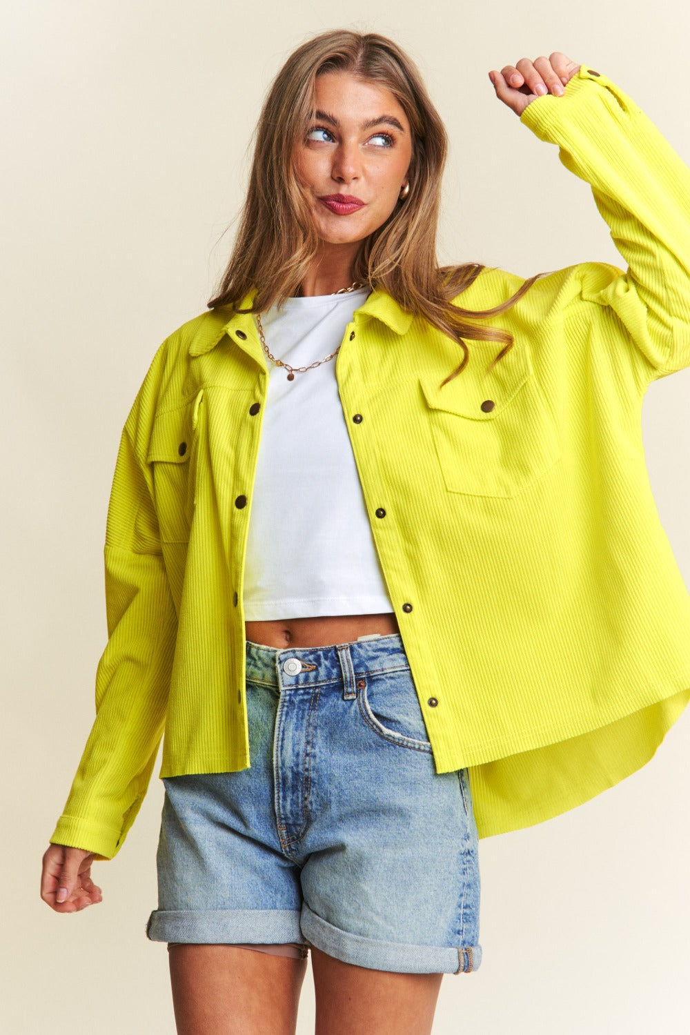 Person wearing a relaxed fit, bright yellow J.NNA Snap Down Long Sleeve High Low Shacket over a white top and denim jeans, smiling against a neutral background.