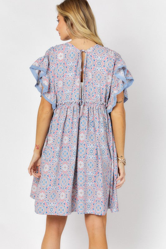 A woman stands against a white background wearing the Printed Short Sleeve Ruffle Kimono over a white top and denim shorts, effortlessly blending style and comfort.