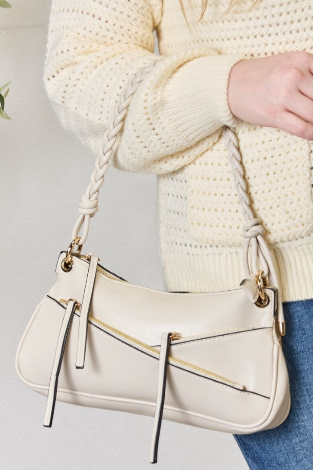 A person exudes bohemian elegance, carrying the SHOMICO Braided Strap Shoulder Bag, expertly crafted with advanced leather techniques and braided handles, while wearing a cream sweater and blue jeans.