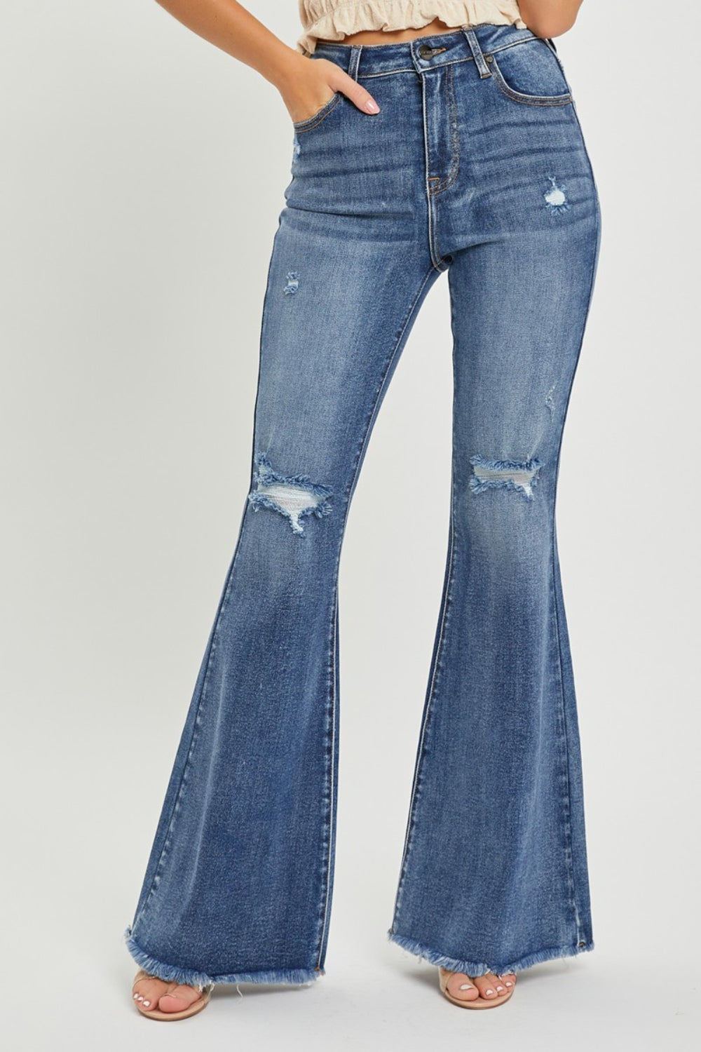 A person is wearing RISEN High Waist Distressed Fare Jeans, characterized by a high-waisted fit with minor rips and frayed hems, standing against a neutral background.