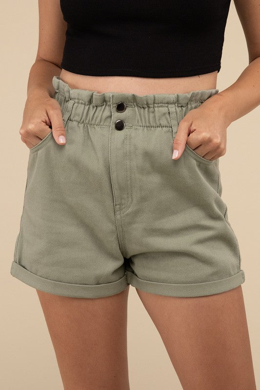 A person wearing light blue Double Buttoned Waistband Denim Shorts with rolled hems, paired with a white ribbed top.