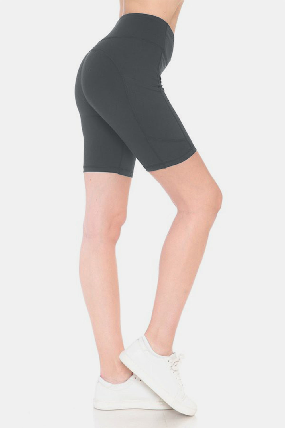 Person placing a smartphone into the side pocket of stylish activewear, featuring Leggings Depot Full Size High Waist Active Shorts made from moisture-wicking fabric.